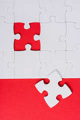 top view of incomplete white puzzles near separate piece isolated on red