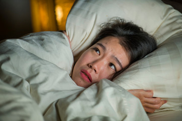 young sleepless beautiful and scared Asian Japanese woman lying on bed awake at night suffering nightmare after watching zombie horror movie in fear and stressed face