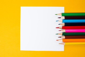 White square and color pencils on a yellow background. Notes for creativity and creative ideas. Empty space for text