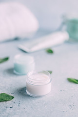 pa and body care products. Blue scrub, white cream face sea salt, towel, mint  on grey background. Beauty skin care. Spa treatment