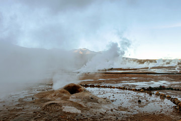 Hot spring at El Tatio Geysers with steaming geysers, hot springs, boiling water all around at sunrise, Chile, South America