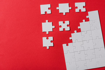 top view of connected and separate jigsaw puzzle pieces isolated on red