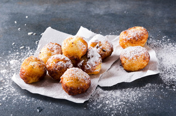 Closeupof deep fried cheese balls with powdered sugar on the baking paper, rustuc grey surface