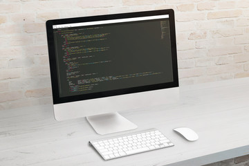 Developer computer with code on display. Clean office desk.