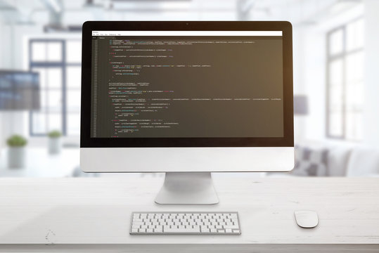 Computer display with code editor. The concept of a developer workplace. The office is in the background.