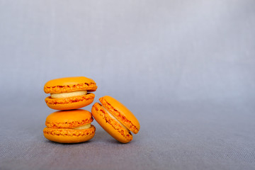 Stack of fresh tasty orange macarons sandwich cookies on gray background. Copy space. French confectionery