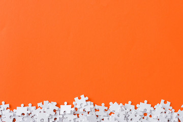 top view of incomplete puzzle pieces isolated on orange with copy space