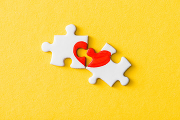 top view of jigsaw puzzle pieces with drawn red heart isolated on yellow