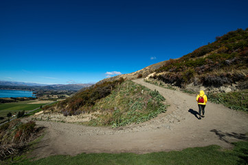 Woman hiker walk on the rough trail with beautiful blue sky at the way to Roys Peaks in Wanaka,...