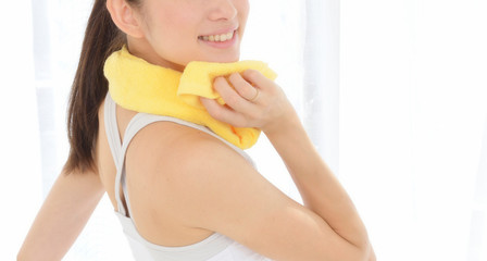 窓辺で汗を拭く女性