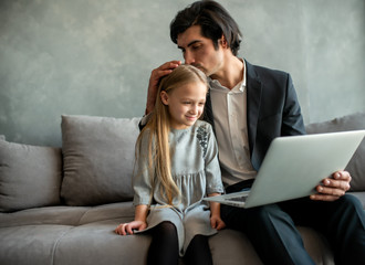 Happy little girl watching a movie on the computer with her father