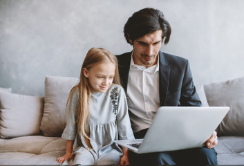 Obraz premium Happy little girl watching a movie on the computer with her father