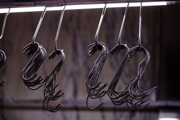 Row of metal butcher's hooks against soft grey background