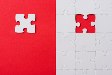 top view of unfinished white puzzles near separate piece isolated on red