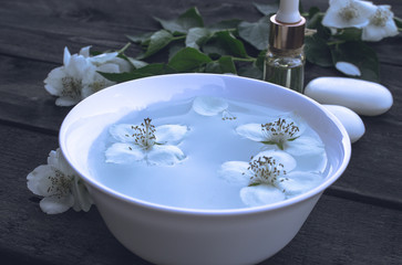 Essential aromatic oil with jasmine on wooden background.