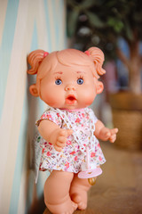 Cute doll sits on the wood background.