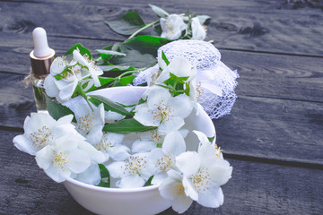 Essential aromatic oil with jasmine on wooden background.