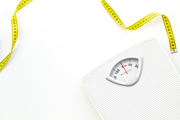 Diet concept with scale and measuring tape for weight loss on white background top view mock up