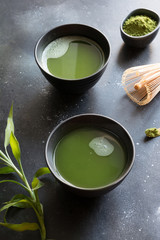 Organic two green matcha tea in bowl on black table.