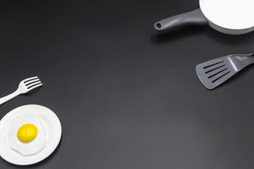 White plastic tableware and kitchenware for children's play are placed diagonally on the black desktop.