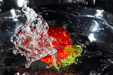Splash of water towards the viewer from falling strawberries