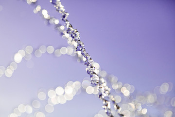 Water droplets frozen in the air with splashes and chain bubbles on a pink and purple isolated background in nature. Clear and transparent liquid symbolizing health and nature.