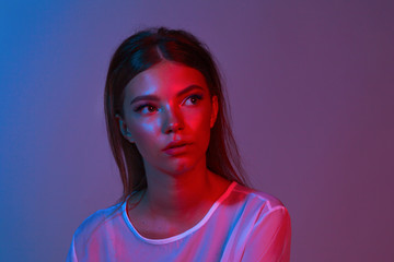 Neon close up portrait of young woman. Studio shot. Model posing in purple, red and pink lights....