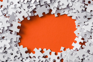 top view of frame of white jigsaw puzzle pieces on orange