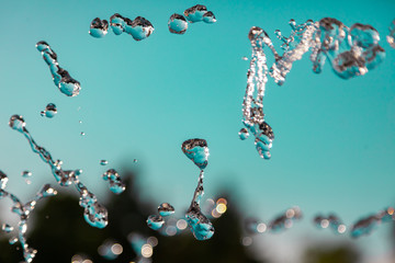 Water droplets frozen in the air with splashes and chain bubbles on a green and turquoise isolated...