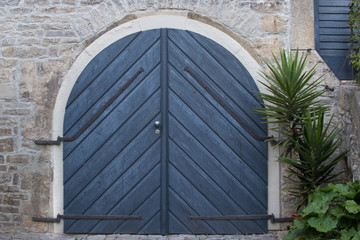 Fototapeta na wymiar Blaues Holztor in Natursteinfassade - Blue wooden gate in natural stone facade