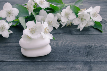 Fototapeta na wymiar Cosmetic soap and white jasmine flowers with green leaves lie on a wooden background. There is a place for your text.