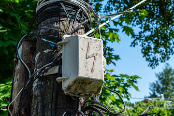 Old electroguard against the background of the confused wires on an old wooden column. Selective focus.