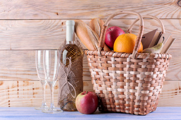 Picnic basket with wine fruit and other products on a natural wooden background. Summer rest ....