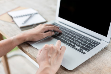 Fototapeta premium Woman hand using laptops and has a notebook and a pen with warm light