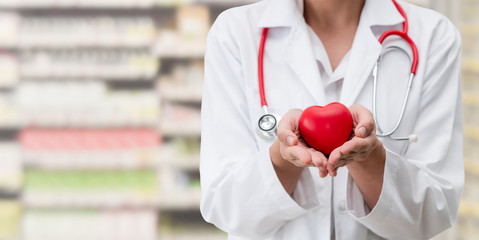 Doctor holding a red heart at hospital office. Medical health care and doctor staff service concept.