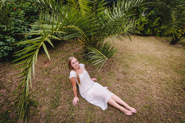Beautiful, young, slender, long-haired blond girl in white long dress. A woman poses against the...