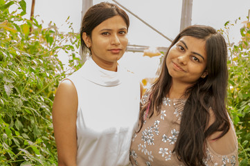 attractive Indian girls posing in garden in greenhouse with tomatoes and vegetables..Closeup...