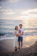 Loving happy young couple hugging and smiling at the sea beach. Waves. Against the background of the sea. Honeymoon. Vacation. Turkey. Night. Evening. Sunset. Close up