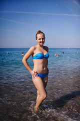 Beautiful young slim girl standing in water at the sea beach. In a blue bathing suit. Turkey. vacation. Vacation. Sunlight. Place for text Close up. Summer vacation, honeymoon.