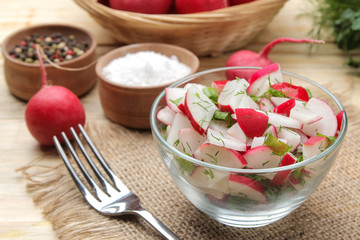 Fresh radish and cucumber salad and greens on a natural wooden table. Salad of spring vegetables. ingredients for making salad.