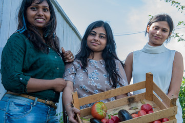 attractive Indian girls posing in garden in greenhouse with tomatoes and vegetables..Closeup...