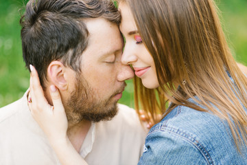 the girl and the guy are sitting on the grass near the blossoming lilac bush in the spring in the park and both are denying themselves. concept of a relaxing holiday in a weekend in nature