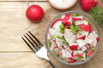 Fresh radish and cucumber salad and greens on a natural wooden table. Salad of spring vegetables. ingredients for making salad. top view