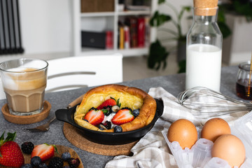 Dutch baby pancake with fresh berries, cup of cappuccino