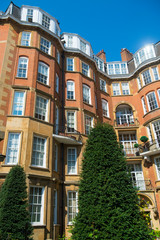 Fototapeta na wymiar Bright scenic view of traditional red brick architecture in a posh London, England neighborhood under bright blue sky