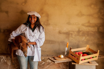 Attractive Indian woman cook posing with red pig. Closeup portrait of young beautiful woman. Positive emotions, facial expressions, feelings, signs and symbols, body language. white chef uniform