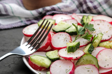 Fresh radish and cucumber salad and greens on a black concrete table. Salad of spring vegetables. ingredients for making salad.