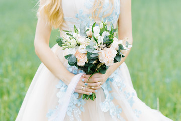 beautiful delicate wedding bouquet white peach in the hands of the bride, the ribbon of the bouquet develops in the wind