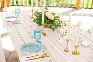 Decorated table for dinner for two person, with plates knife, fork, cheese, wine, wine glasses and flowers in a copper vase.