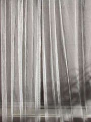 Low angle sunlight shining through a pair of sheer curtains